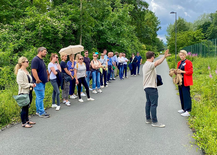 Eine Gruppe Menschen steht auf einem Weg und lässt sich etwas erklären.