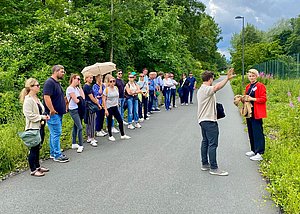 Eine Gruppe Menschen steht auf einem Weg und lässt sich etwas erklären.